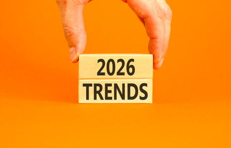 2026 Trends new year symbol. Concept words 2026 Trends on beautiful wooden blocks. Beautiful orange paper background. Businessman's hand. Business and 2026 Trends new year concept. Copy space.の写真素材