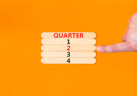 2nd second quarter 2 symbol. Concept word Quarter 2 on beautiful wooden sticks. Beautiful orange background. Businessman's hand. Business, happy 2nd second quarter 2 Q2 concept. Copy space.の写真素材