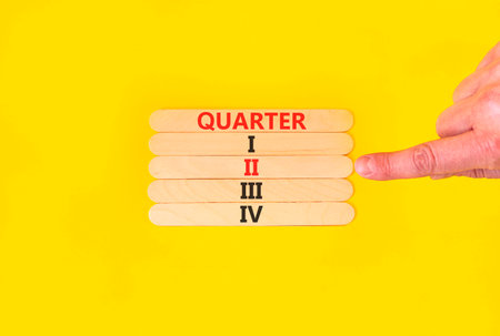 2nd second quarter 2 symbol. Concept word Quarter 2 on beautiful wooden sticks. Beautiful yellow background. Businessman's hand. Business, happy 2nd second quarter 2 Q2 concept. Copy space.の写真素材