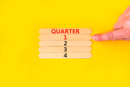 1st first quarter 1 symbol. Concept word Quarter 1 on beautiful wooden sticks. Beautiful yellow background. Businessman's hand. Business, happy 1st first quarter 1 Q1 concept. Copy space.の写真素材