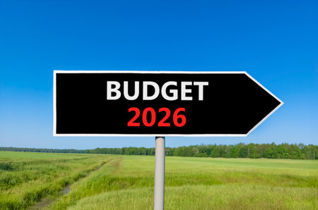 Budget 2026 symbol. Concept words Budget 2026 on beautiful black road sign. Beautiful green grass field forest and blue sky background. Business and budget 2026 concept. Copy space.の写真素材