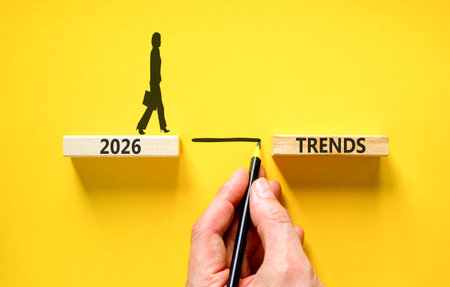 2026 Trends symbol. Concept words 2026 Trends on beautiful wooden blocks. Beautiful yellow background. Businessman holds pencil. Businesswoman icon. Business 2026 Trends new year concept. Copy space.の写真素材