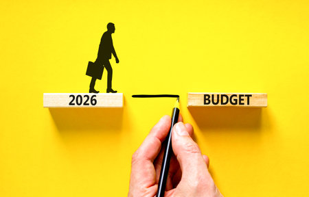 2026 Budget symbol. Concept words 2026 Budget on beautiful wooden blocks. Beautiful yellow background. Businessman holds pencil. Businessman icon. Business and 2026 budget concept. Copy space.の写真素材