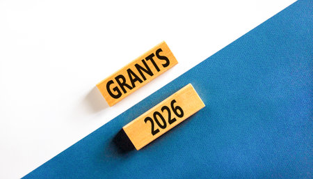 Grants 2026 symbol. Concept words Grants 2026 on beautiful wooden blocks. Beautiful white and blue paper background. Business and grants 2026 concept. Copy space.の写真素材