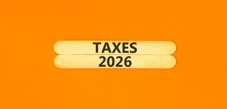 Taxes 2026 new year symbol. Concept words Taxes 2026 on beautiful wooden sticks. Beautiful orange paper background. Business and taxes 2026 new year concept. Copy space.の写真素材