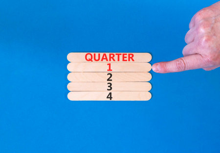 1st first quarter 1 symbol. Concept word Quarter 1 on beautiful wooden sticks. Beautiful blue background. Businessman's hand. Business, happy 1st first quarter 1 Q1 concept. Copy space.の写真素材