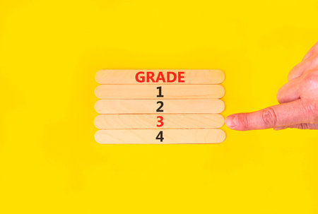 Time to grade 3 symbol. Concept word Grade 1 2 3 4 on beautiful wooden sticks. Businessman's hand. Beautiful yellow background. Business planning and time to grade 3 concept. Copy space.の写真素材
