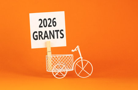 2026 Grants symbol. Concept words 2026 Grants on beautiful white paper on wooden clothespin. Beautiful orange background. Beautiful miniature bicycle. Business and 2026 grants concept. Copy space.の写真素材