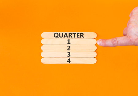 1st first quarter 1 symbol. Concept word Quarter 1 on beautiful wooden sticks. Beautiful orange background. Businessman's hand. Business, happy 1st first quarter 1 Q1 concept. Copy space.の写真素材