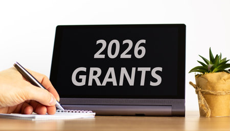 2026 Grants symbol. Concept words 2026 Grants on beautiful black tablet screen. Beautiful white background. Businessman's hand. Business and 2026 grants concept. Copy space.の写真素材