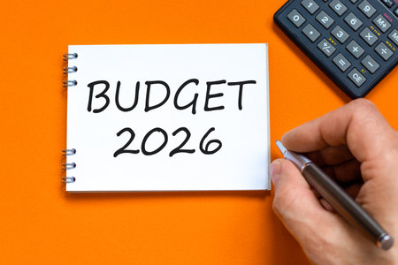 Budget 2026 symbol. Concept words Budget 2026 on beautiful white note. Black calculator. Beautiful orange paper background. Businessman's hand. Business and budget 2026 concept. Copy space.の写真素材