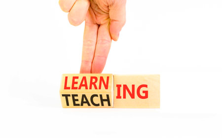 Learning and teaching symbol. Concept words Learning and Teaching on beautiful wooden cubes. Beautiful white background. Psychologist's hand. Business education learning teaching concept. Copy spaceの写真素材