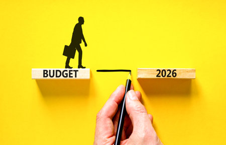 Budget 2026 symbol. Concept words Budget 2026 on beautiful wooden blocks. Beautiful yellow background. Businessman holds pencil. Businessman icon. Business and budget 2026 concept. Copy space.の写真素材