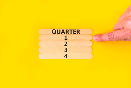 1st first quarter 1 symbol. Concept word Quarter 1 on beautiful wooden sticks. Beautiful yellow background. Businessman's hand. Business, happy 1st first quarter 1 Q1 concept. Copy space.の写真素材