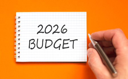 2026 Budget symbol. Concept words 2026 Budget on beautiful white note. Beautiful orange paper background. Businessman's hand with pen. Business and 2026 budget concept. Copy space.の写真素材