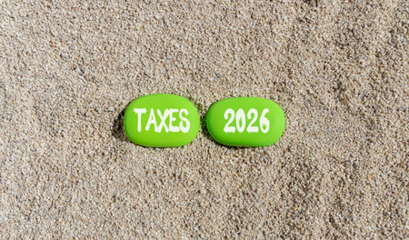 Taxes 2026 new year symbol. Concept words Taxes 2026 on beautiful green stones on sand beach....