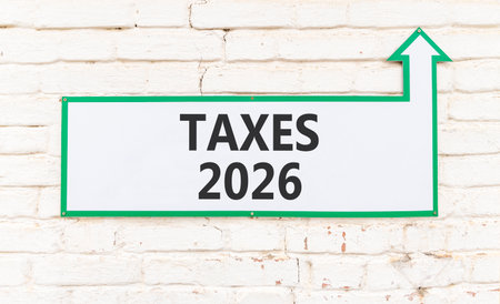 Taxes 2026 new year symbol. Concept words Taxes 2026 on beautiful white sign with arrow. Beautiful old white brick wall background. Business and taxes 2026 new year concept. Copy space.の写真素材