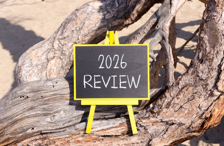 2026 Review symbol. Concept words 2026 Review on beautiful black blackboard. Beautiful old tree and sand background. Business and 2026 review concept. Copy space.の写真素材