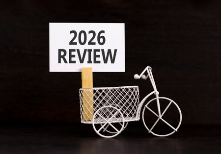 2026 Review symbol. Concept words 2026 Review on beautiful white paper on wooden clothespin. Beautiful black background. Beautiful miniature bicycle. Business and 2026 review concept. Copy space.の写真素材