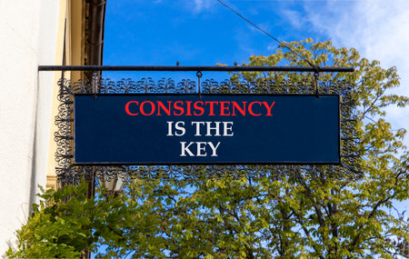 Consistency is the key symbol. Concept words Consistency is the key on black beautiful road sign. Beautiful blue sky and trees background. Business consistency is the key concept. Copy space.の写真素材