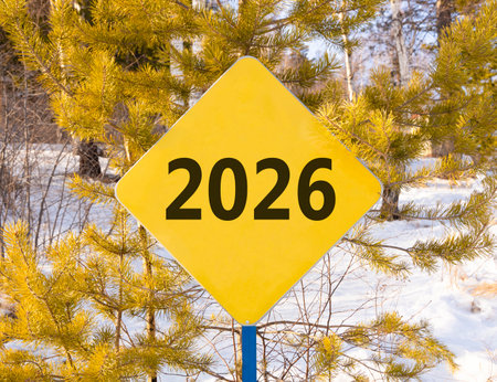 Concept number 2026 on beautiful yellow road sign. Beautiful winter forest background. Business 2026 happy new year concept. Copy space.の写真素材