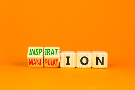 Inspiration or manipulation symbol. Concept words Inspiration and Manipulation on wooden cubes. Beautiful orange background. Psychology inspiration manipulation concept. Copy space.の写真素材