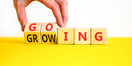 Going and growing symbol. Concept words Going Growing on beautiful wooden blocks. Beautiful white and yellow background. Businessman's hand. Business going and growing concept. Copy space.の写真素材