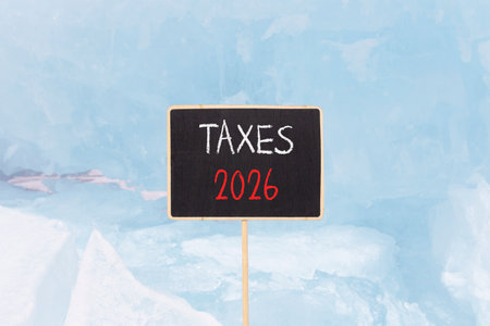 Taxes 2026 new year symbol. Concept words Taxes 2026 on beautiful black blackboard. Beautiful blue lake Baikal ice background. Business and taxes 2026 new year concept. Copy space.の写真素材