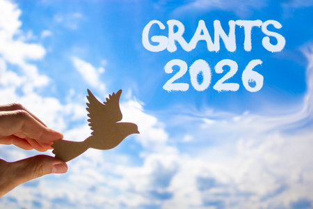 Grants 2026 symbol. Concept words Grants 2026 on beautiful blue sky. Beautiful blue sky background. Businessman's hand holds wooden bird. Business and grants 2026 concept. Copy space.の写真素材