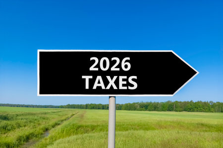 2026 taxes new year symbol. Concept words 2026 taxes on beautiful black road sign. Beautiful green grass field forest and blue sky background. Business and 2026 taxes new year concept. Copy space.の写真素材