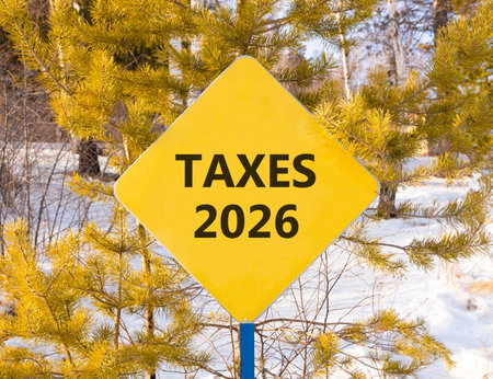 Taxes 2026 new year symbol. Concept words Taxes 2026 on beautiful yellow road sign. Beautiful winter forest background. Business and taxes 2026 new year concept. Copy space.の写真素材