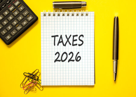 Taxes 2026 new year symbol. Concept words Taxes 2026 on beautiful white note. Beautiful yellow background. Black pen. Beautiful black calculator. Business and taxes 2026 new year concept. Copy space.の写真素材