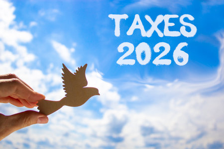Taxes 2026 new year symbol. Concept words Taxes 2026 on beautiful blue sky. Beautiful blue sky background. Businessman's hand holds wooden bird. Business and taxes 2026 new year concept. Copy space.の写真素材
