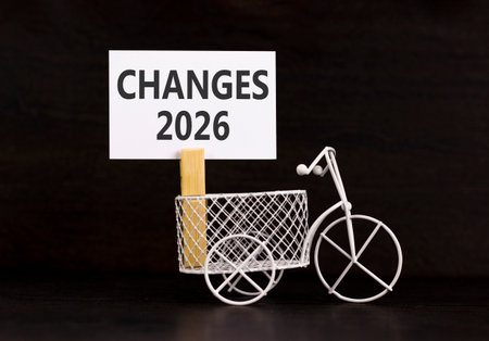 Changes 2026 symbol. Concept words Changes 2026 on beautiful white paper on wooden clothespin. Beautiful black background. Beautiful miniature bicycle. Business and changes 2026 concept. Copy space.の写真素材