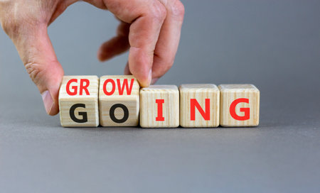 Going and growing symbol. Concept words Going Growing on beautiful wooden blocks. Beautiful gray...