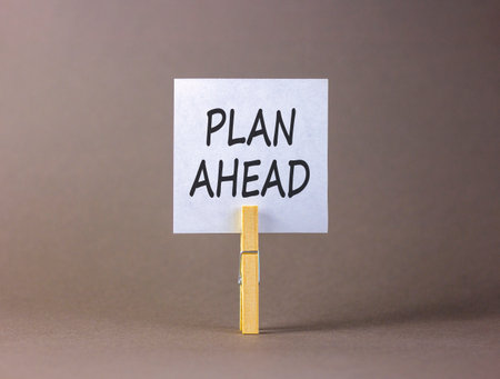 Plan ahead symbol. Concept word Plan ahead on beautiful white paper. Beautiful wooden clothespin. Beautiful gray background. Business plan ahead concept. Copy space.の写真素材