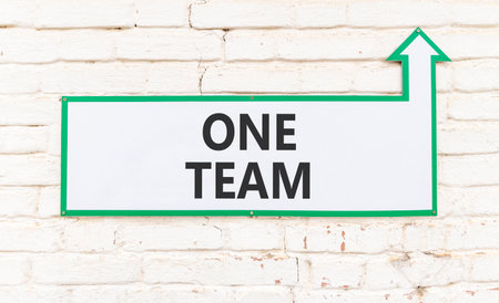 One team symbol. Concept word One team on beautiful white sign on white brick wall. Beautiful white brick wall background. Business one team concept. Copy space.の写真素材