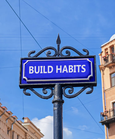 Build habits symbol. Concept word Build habits on beautiful blue road sign. Beautiful blue sky and buildings background. Business build habits concept. Copy space.の写真素材