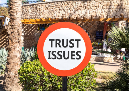 Trust issues symbol. Concept word Trust issues on beautiful red and white road sign. Beautiful palm tree and market background. Business trust issues concept. Copy space.の写真素材
