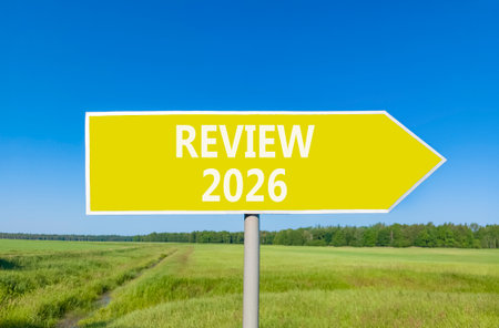Review 2026 symbol. Concept words Review 2026 on beautiful yellow road sign. Beautiful green grass field forest and blue sky background. Business and review 2026 concept. Copy space.の写真素材