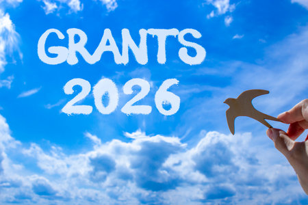 Grants 2026 symbol. Concept words Grants 2026 on beautiful blue sky. Beautiful blue sky background. Businessman's hand holds wooden bird. Business and grants 2026 concept. Copy space.の写真素材