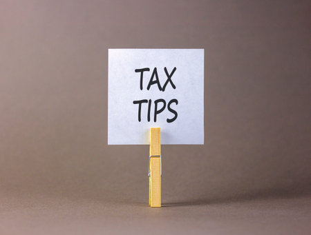 Tax tips symbol. Concept word Tax tips on white paper. Wooden clothespin. Gray background. Business tax tips concept. Copy space.の写真素材