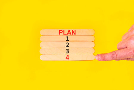 Time to plan 4 symbol. Concept word Plan 1 2 3 4 on beautiful wooden sticks. Businessman's hand. Beautiful yellow background. Business planning and time to plan 4 concept. Copy space.の写真素材