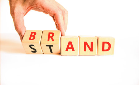 Brand or stand symbol. Concept words Brand Stand on beautiful wooden blocks. Beautiful white background. Businessman's hand. Business brand or stand concept. Copy space.の写真素材