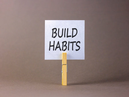 Build habits symbol. Concept word Build habits on beautiful white paper. Beautiful wooden clothespin. Beautiful gray background. Business build habits concept. Copy space.の写真素材
