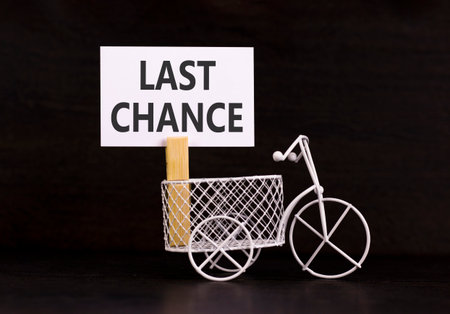 Last chance symbol. Concept word Last chance on beautiful white paper. Beautiful wooden clothespin. Miniature white bicycle. Beautiful black background. Business last chance concept. Copy space.の写真素材