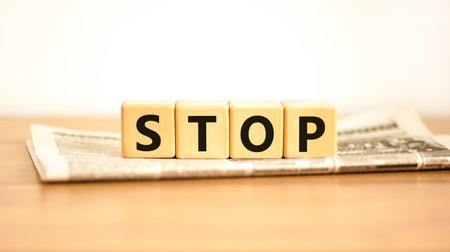 Stop symbol. Concept word Stop on beautiful wooden blocks on newspaper. Beautiful wooden table white background. Business, lifestyle, support and stop concept. Copy space.の写真素材