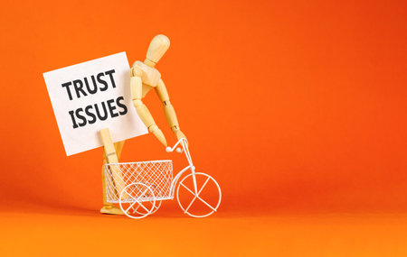 Trust issues symbol. Concept word Trust issues on beautiful white paper. Beautiful wooden clothespin. Businessman's model. Beautiful orange background. Business trust issues concept. Copy space.の写真素材