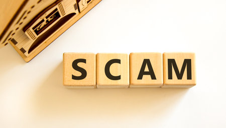 Scam symbol. Concept word Scam on beautiful wooden blocks. Beautiful wooden house. Beautiful white table white background. Business, lifestyle, support and scam concept. Copy space.の写真素材