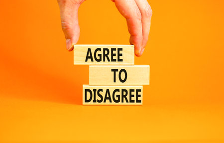 Agree to disagree symbol. Concept words Agree to disagree on beautiful wooden block. Businessman's hand. Beautiful orange background. Business and agree to disagree concept. Copy space.の写真素材